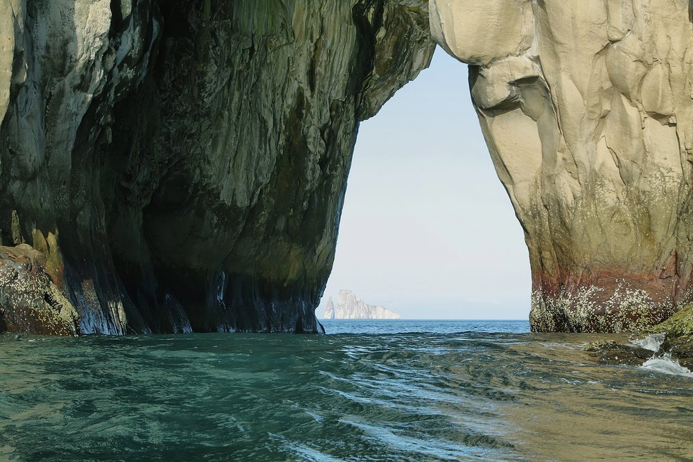 Cerro Brujo, also known as Witch Hill, has a natural stone arch, through which we can see Kicker Rock