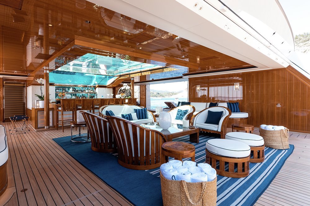 The beach club on the 96.6m (316.8ft) Feadship FAITH, for charter with Burgess, opens on three sides and sits beneath a glass-bottomed pool