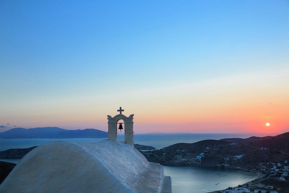 Sail by white washed buildings silhouetted on the skyline