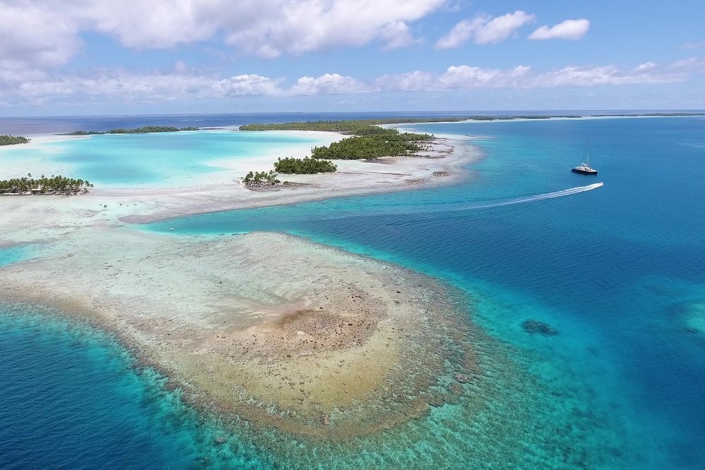 The 44.2m sailing catamaran HEMISPHERE anchored off a blue lagoon in the Tuamotus